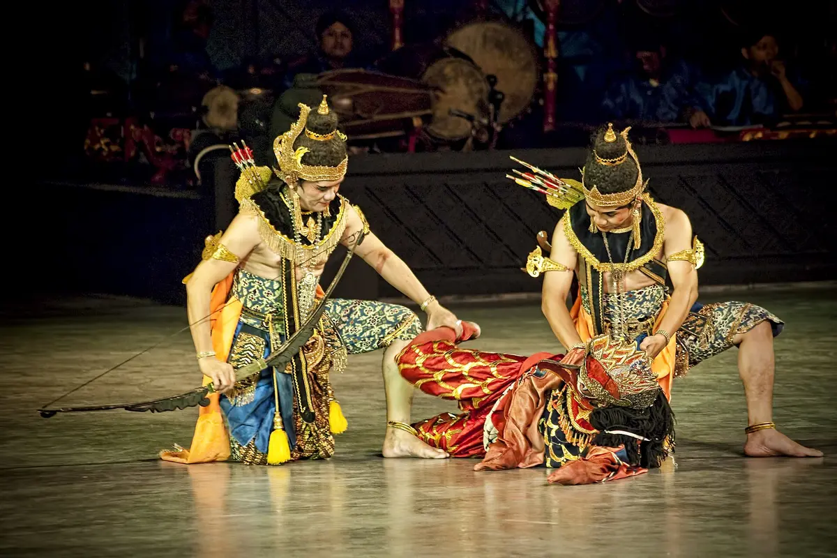 Rama, holding a bow, kneels beside the wounded eagle-king Jatayu on the Prambanan stage, with gamelan musicians and their drums and gongs behind